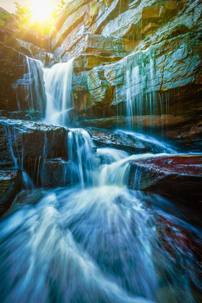 Ein belebender Wasserfall, dessen klares Wasser im Sonnenlicht über Felsen strömt.