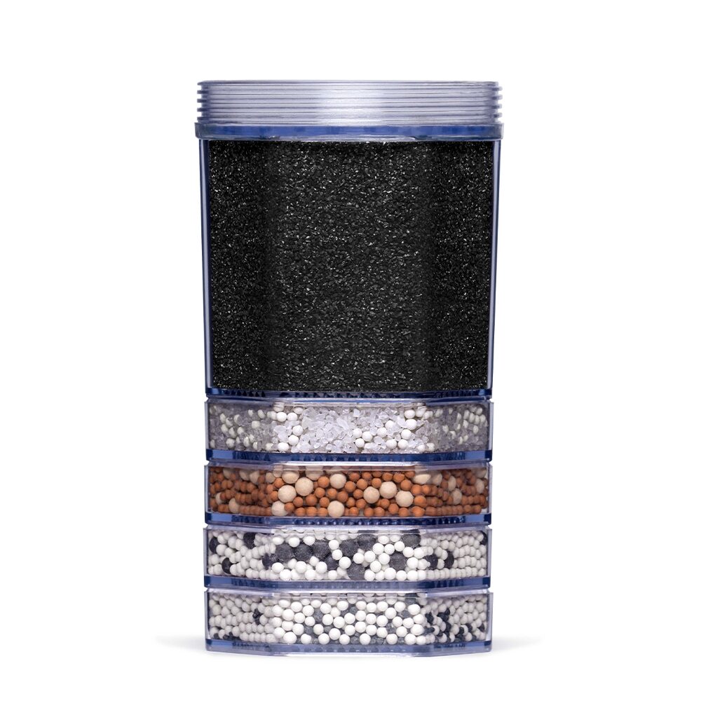 Eine transparente Wasserfilter-Kartusche mit sichtbaren Schichten aus Aktivkohle und verschiedenen Mineralien zur Wasseraufbereitung.