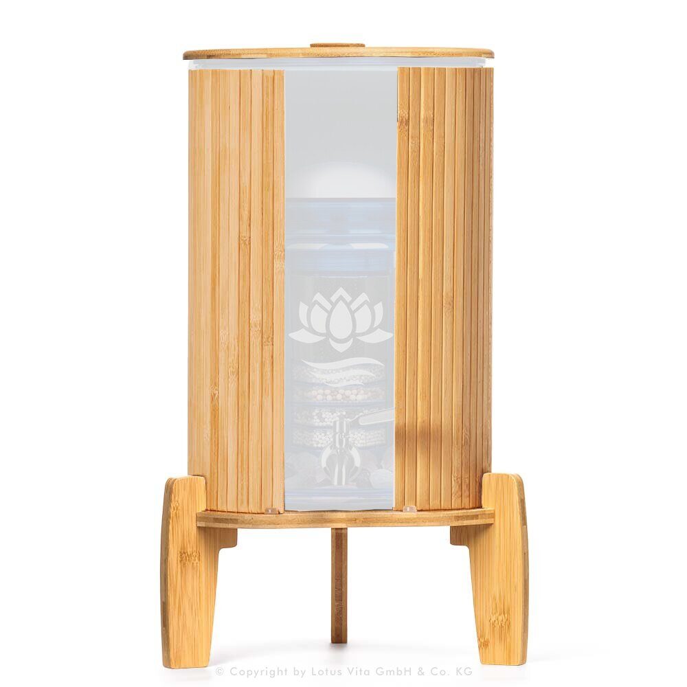 Ein Stand-Wasserfilter mit 8 Litern Fassungsvermögen, umhüllt von einem Lichtschutz aus Bambus, stehend auf einem passenden Bambussockel.