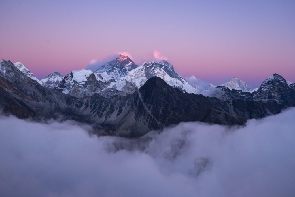 Majestätischer, schneebedeckter Gipfel des Mount Everest, erhaben über einem Wolkenmeer bei Sonnenaufgang.