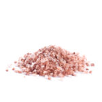 Ein Haufen grobkörniges, rosa Kristallsalz auf einer reinweißen Oberfläche.