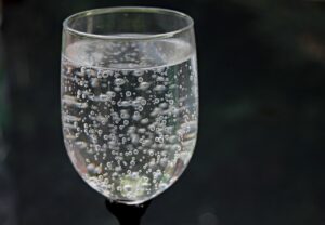 Ein Glas mit sprudelndem Mineralwasser vor einem dunklen Hintergrund.