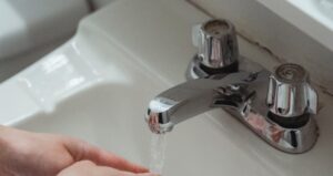 Eine Person wäscht sich die Hände unter fließendem Wasser aus einem Wasserhahn, was die tägliche Nutzung von Leitungswasser symbolisiert.