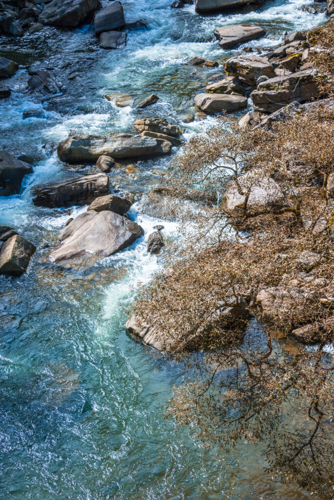 Ein klarer Gebirgsbach fließt schwungvoll über Felsen und Steine, ein Symbol für reines, natürliches Wasser.