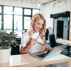 Eine Frau sitzt lächelnd vor ihrem Laptop und nimmt am Lotus Vita Empfehlungsprogramm teil.